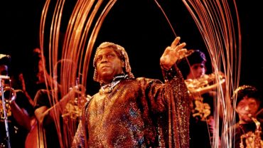 Sun Ra under copper arches with Arkestra on stage - Photo by Leni Sinclair
